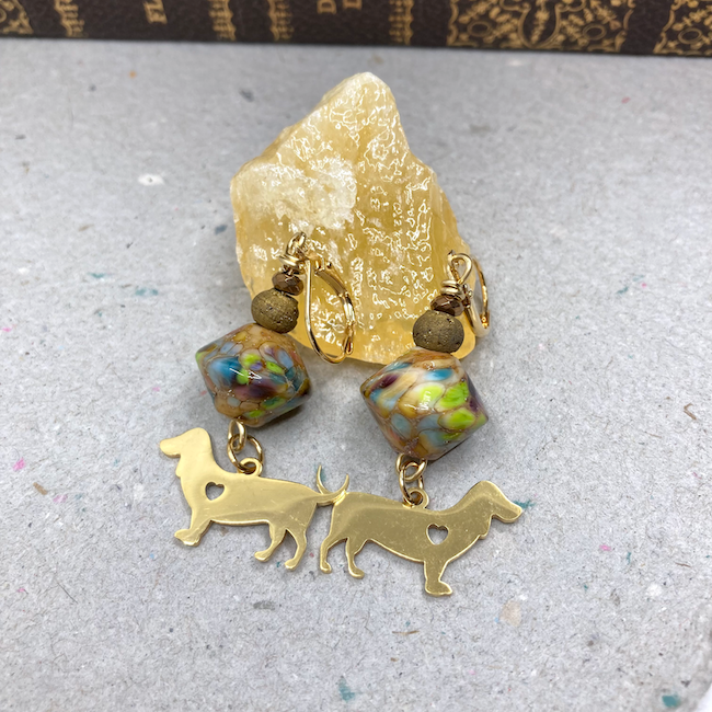 Earrings with gold and multicolor beads and gold dog charms with heart cutout. 
