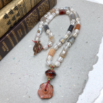 Necklace with white, peach, and grey beads, rusty tone lampwork beads for a pendant and a copper toggle clasp.