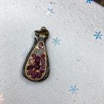 Metal cat bezel pendant with metal heart and small ruby chips in center.